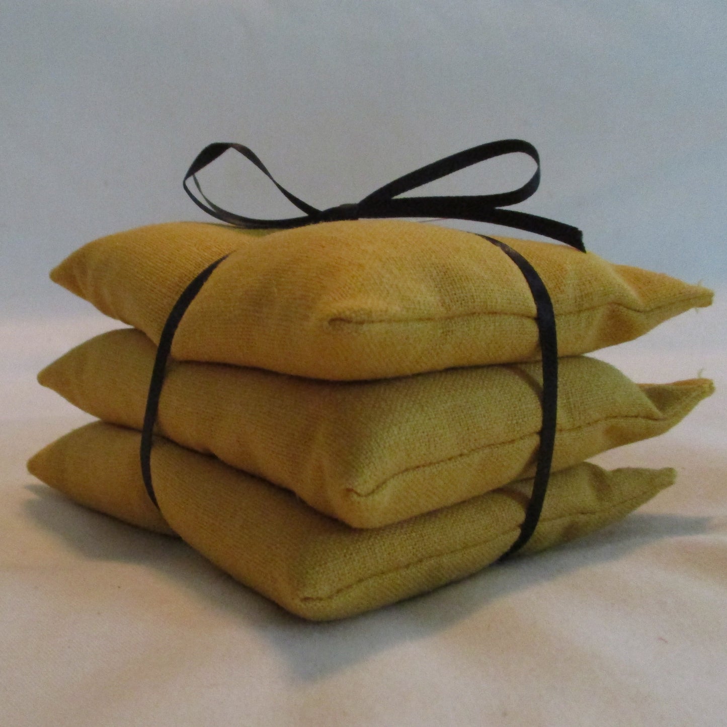 Stack of yellow pillows tied with black ribbon on a white background