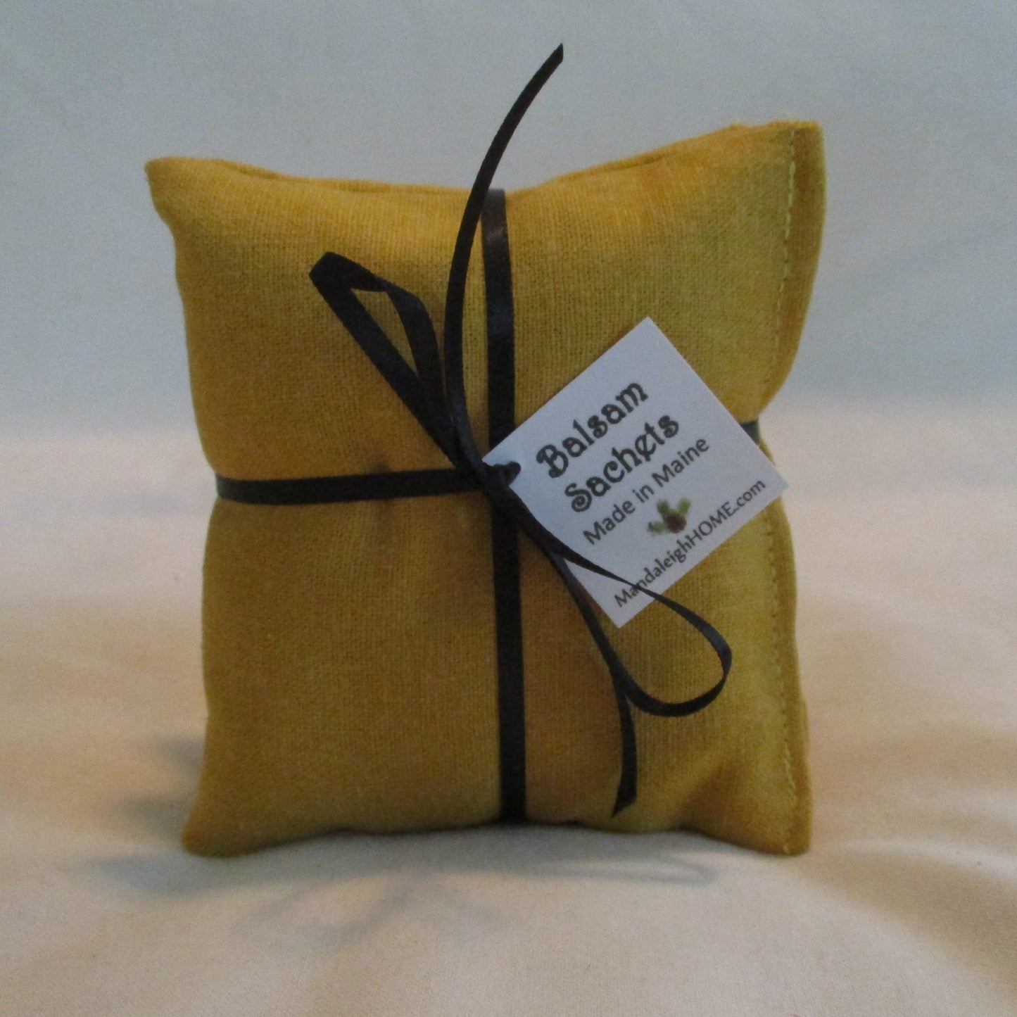 Yellow sachet with a black ribbon and label on a white background