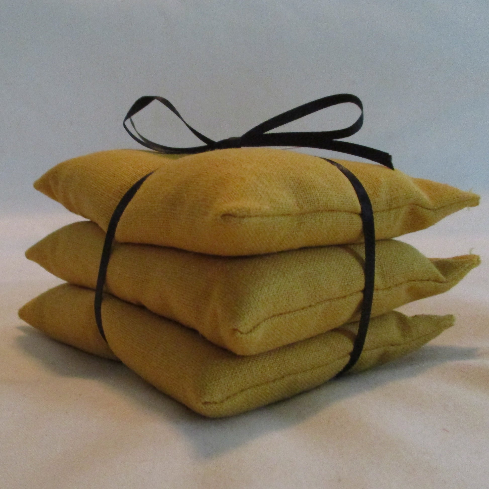 Stack of yellow pillows tied with black ribbon on a white background